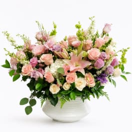 Pastel flower arrangement in a white vase with roses, lilies, and mixed blooms