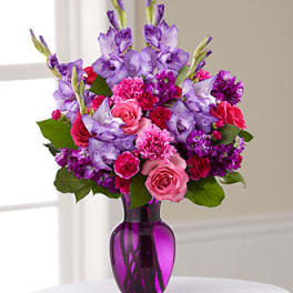 Pink and purple mixed bouquet in a purple glass vase