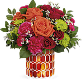 Mixed bouquet of orange and pink roses in a patterned vase