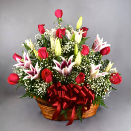 Basket arrangement of red roses and white lilies with a red ribbon