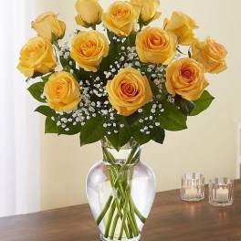 Yellow roses arranged in a clear glass vase with baby's breath