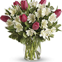 Pink tulips and white alstroemeria arranged in a clear glass vase