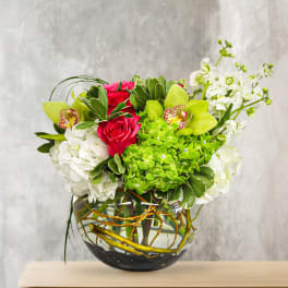 Bouquet of pink roses, green orchids, and white blooms in a glass vase