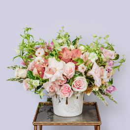 Pink and peach floral arrangement in a white vase