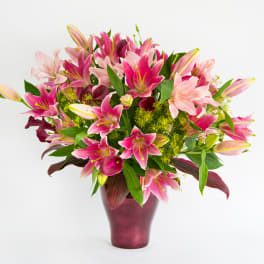 Pink lilies arranged in a burgundy vase