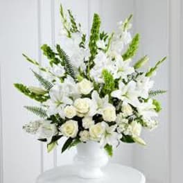 White floral arrangement in a white vase with tall green accents
