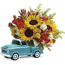 Bouquet of sunflowers and red roses in a turquoise toy truck
