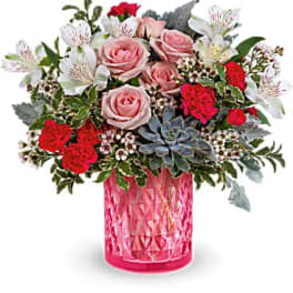 Pink and red roses with white alstroemeria in a pink glass vase