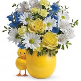 Yellow vase with mixed flowers and a small chick figurine