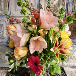 Mixed bouquet of lilies, roses, and a red gerbera daisy in a glass vase