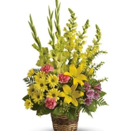 Yellow and pink flowers arranged in a wicker basket