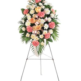 Standing floral spray with pink carnations, peach roses, and white daisies