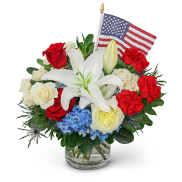 Red, white, and blue floral arrangement with an American flag in a glass vase