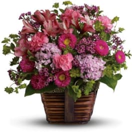 Pink and purple mixed flowers arranged in a wicker basket