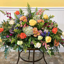 Large mixed flower arrangement with roses, hydrangeas, and snapdragons on a stand