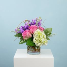 Pink roses and purple flowers in a glass vase