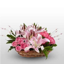 Pink lilies and roses arranged in a wicker basket