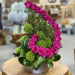Pink roses arranged with green pom-pom accents in a low round container