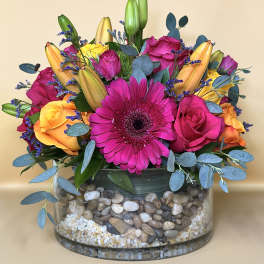 Bright mixed bouquet with pink gerbera, roses, and lilies in a glass vase