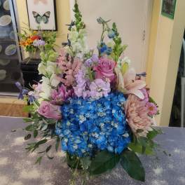 Mixed bouquet with blue hydrangeas, pink roses, lilies, and lavender flowers