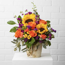 Bouquet of sunflowers and orange roses in a rustic vase