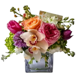 Mixed bouquet with roses, orchids, and tulips in a square glass vase