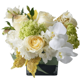 White and pale yellow floral arrangement in a black vase