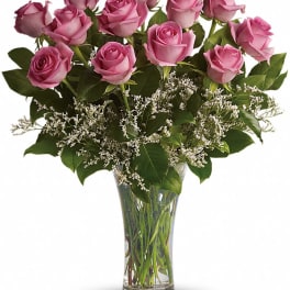 Pink roses arranged in a clear glass vase with white filler flowers