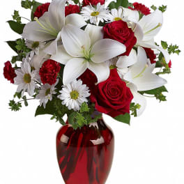 Bouquet of white lilies, red roses, and daisies in a red glass vase