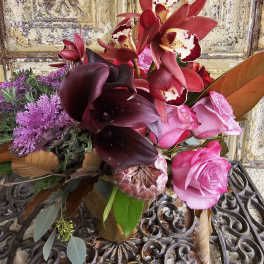 Bouquet of pink roses, dark calla lilies, and red orchids