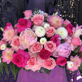 Pink and white rose bouquet with dahlia-like blooms in a clear vase