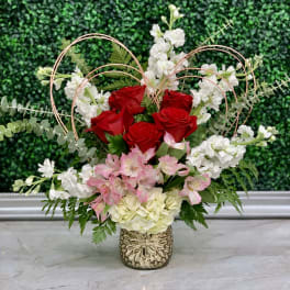 Red roses and pink-white flowers in a decorative vase