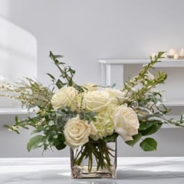 Cream roses and pale hydrangeas in a clear square vase