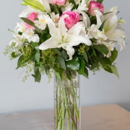 Pink roses and white lilies arranged in a tall glass vase