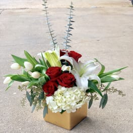 Red roses and white lilies in a square box with tall silver foliage