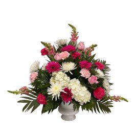 Pink and white mixed flower arrangement in a white urn vase