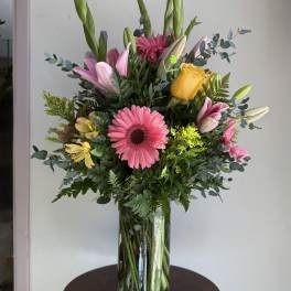 Mixed bouquet in a glass vase with pink, yellow, and white flowers