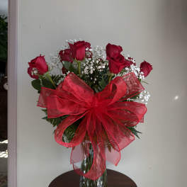 Red roses in a glass vase with a large red bow