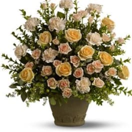 Arrangement of pale roses and carnations in a dark vase