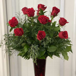 Red roses arranged in a tall burgundy vase