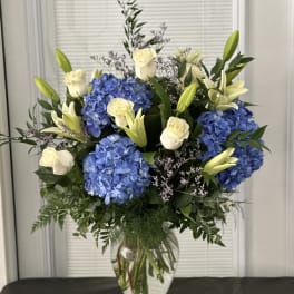 Blue hydrangeas and white roses in a clear glass vase