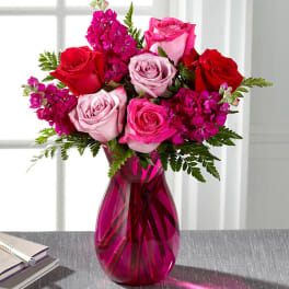 Pink and red roses in a magenta glass vase