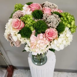 Pink roses and white hydrangeas arranged in a glass vase