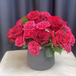 Pink and red roses arranged in a gray vase
