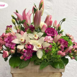 Pink lilies, white orchids, and magenta flowers in a wooden box