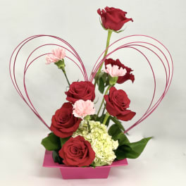 Red roses and pink carnations in a pink heart-shaped container