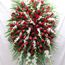Large standing spray of red roses and white orchids on a white backdrop