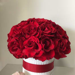 Red rose bouquet in a white textured vase with a red ribbon