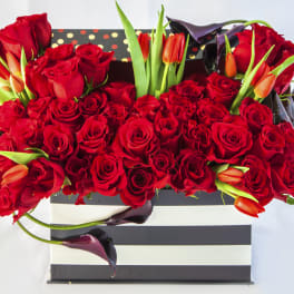 Red roses and orange tulips in a striped gift box
