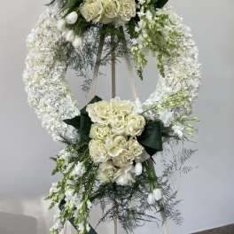 White floral standing wreath on an easel with roses and orchids